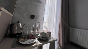 A neatly arranged breakfast table with a kettle, glasses, water bottles, and a plate with food packets.
