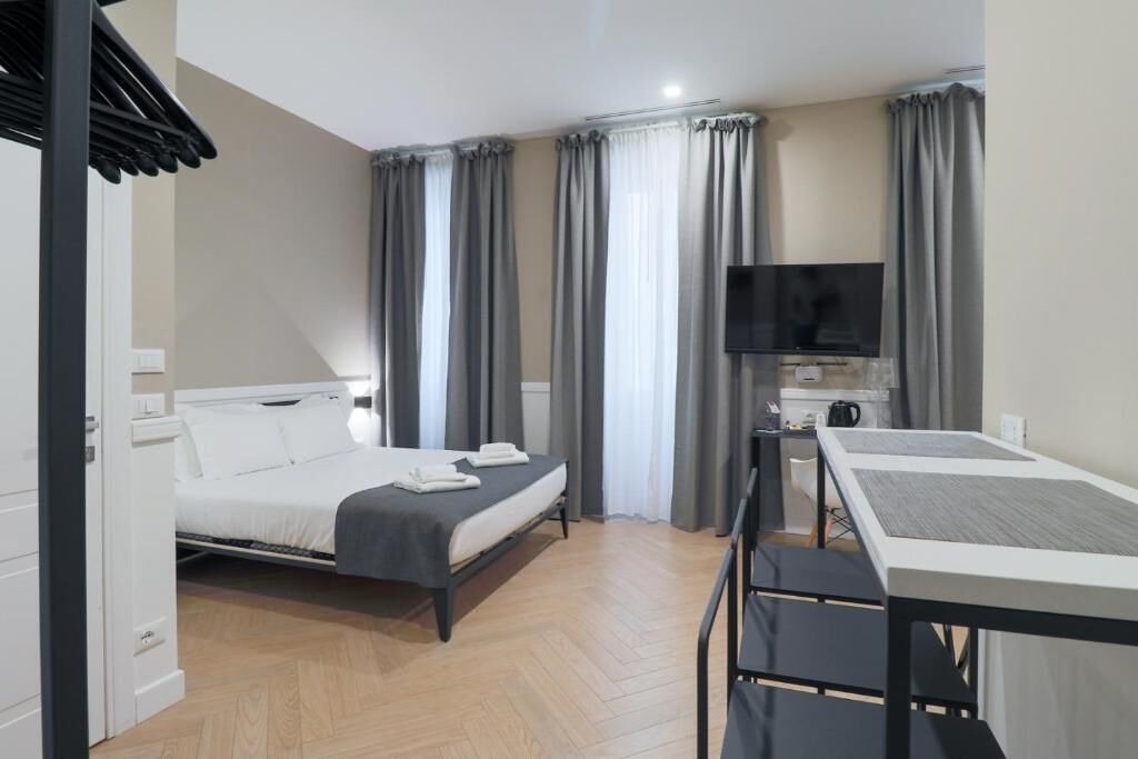 Ein modernes Hotelzimmer mit Bett, Schreibtisch und Fernseher.