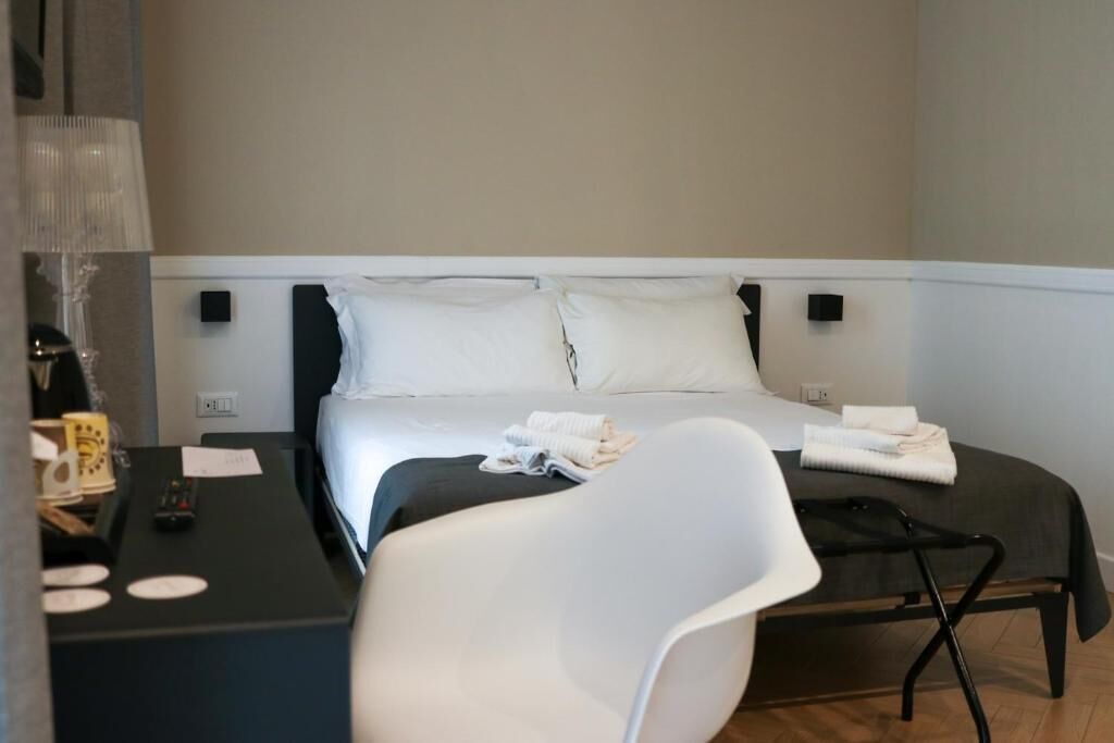 Una habitación de hotel con una cama, un escritorio con una lámpara y una silla.