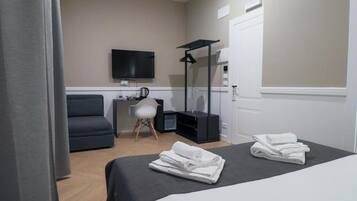 A hotel room with a bed, a desk, a chair, a TV, and a mirror.