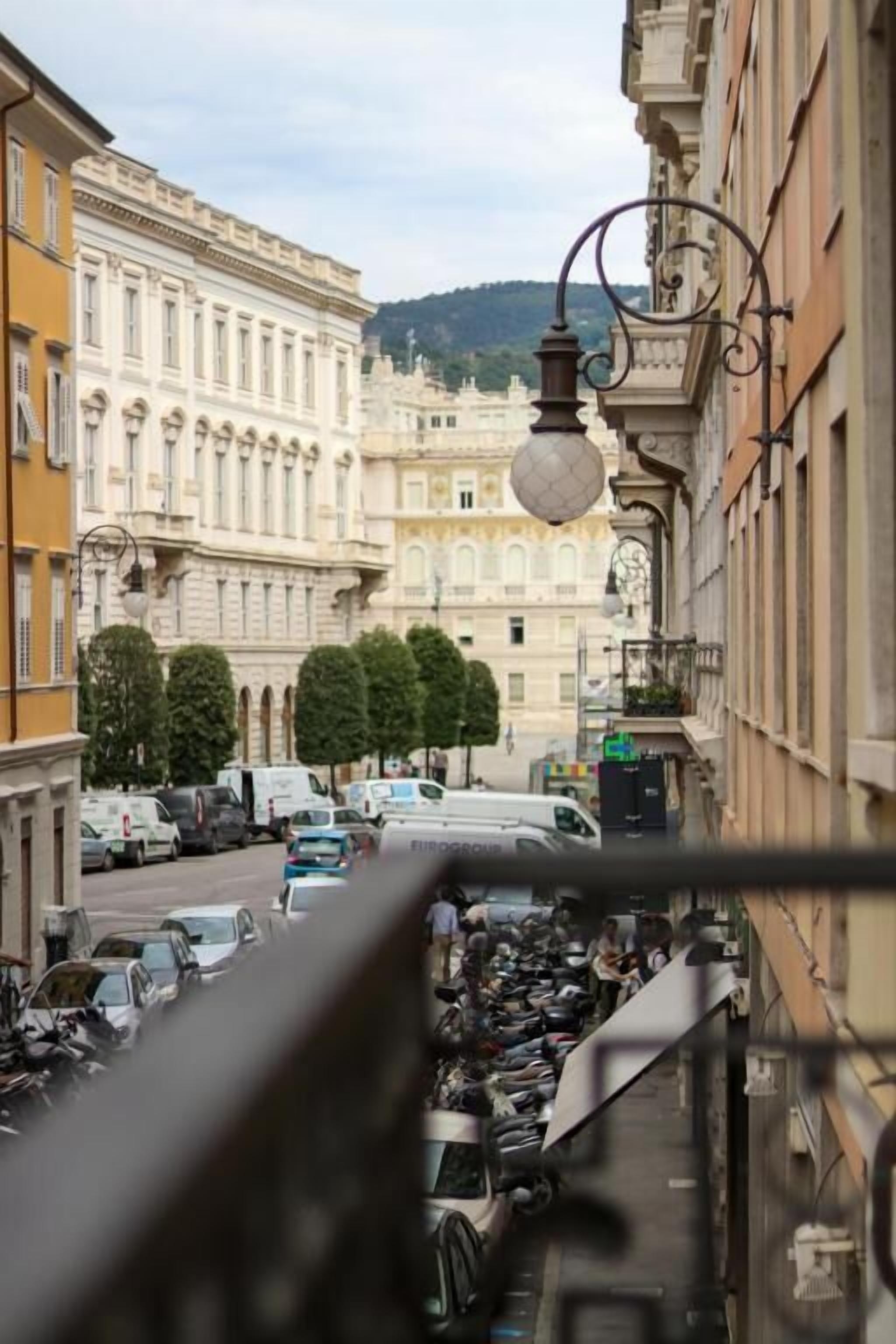 A street view with parked cars and a building with classical architecture.