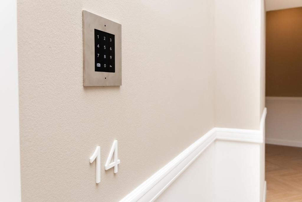 Un teclado numérico en la pared y un letrero blanco con el número 14, indicando el número de una habitación o lugar.