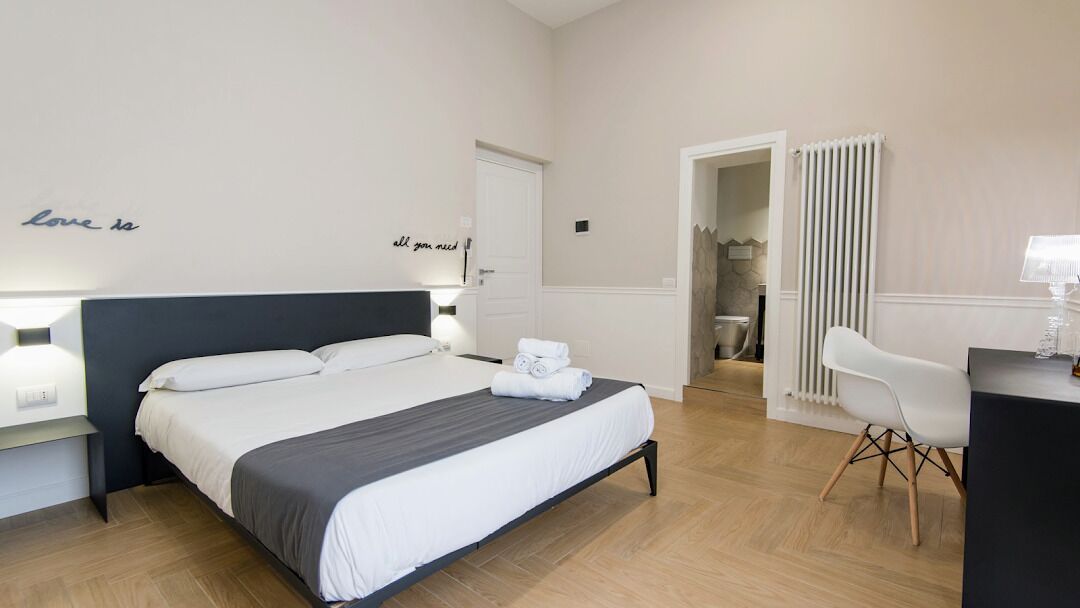 Une chambre d’hôtel moderne avec un lit bien fait, un bureau avec une lampe et une chaise.