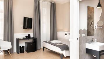 A modern hotel room with a bed, desk, and TV.