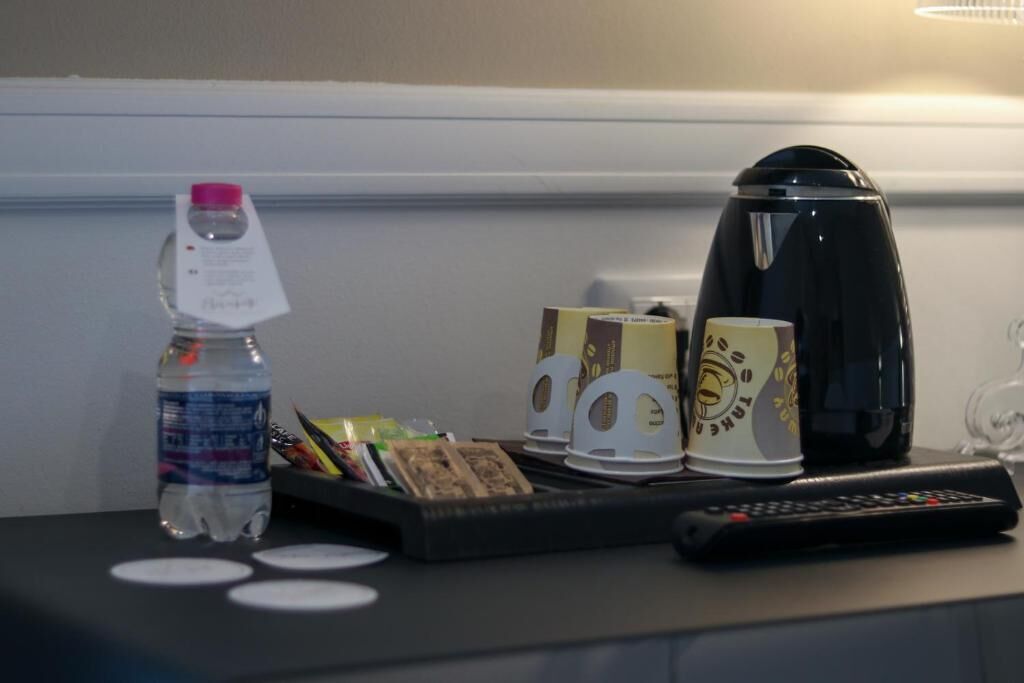Habitación de hotel con cafetera, botella de agua, bandeja con aperitivos y control remoto sobre la mesa.