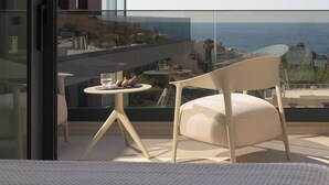 A modern balcony with a view of the sea, a table with a glass and two decorative items, and a chair. - Ayeria Villa · Design Retreat by the Beach & Shops (Panormos in Rethymno)