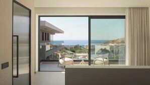 A modern hotel room with a balcony, a dining area, and a view of the sea. - Ayeria Villa · Design Retreat by the Beach & Shops (Panormos in Rethymno)