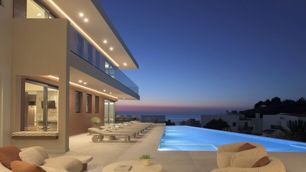 A modern outdoor lounge area with a pool, seating, and a view of the ocean at dusk. - Ayeria Villa · Design Retreat by the Beach & Shops (Panormos in Rethymno)
