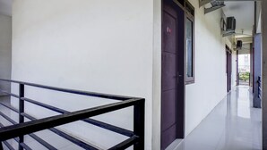 A corridor with a metal railing, a door, and air conditioning units on the wall. - Hotel O Banda Aceh near UIN formerly Alif Guest House Syariah (Banda Aceh)