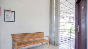 A wooden bench in a hallway with a white wall and a door to the right. - Hotel O Banda Aceh near UIN formerly Alif Guest House Syariah (Banda Aceh)