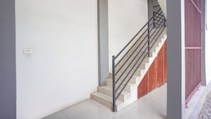A staircase with a metal handrail and a red railing, leading to a landing with a white wall and a light switch. - Hotel O Banda Aceh near UIN formerly Alif Guest House Syariah (Banda Aceh)
