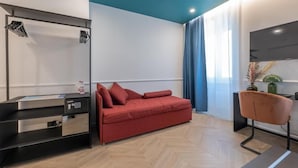 A modern room with a red sofa, a black desk with drawers, a chair, and a large window with curtains.