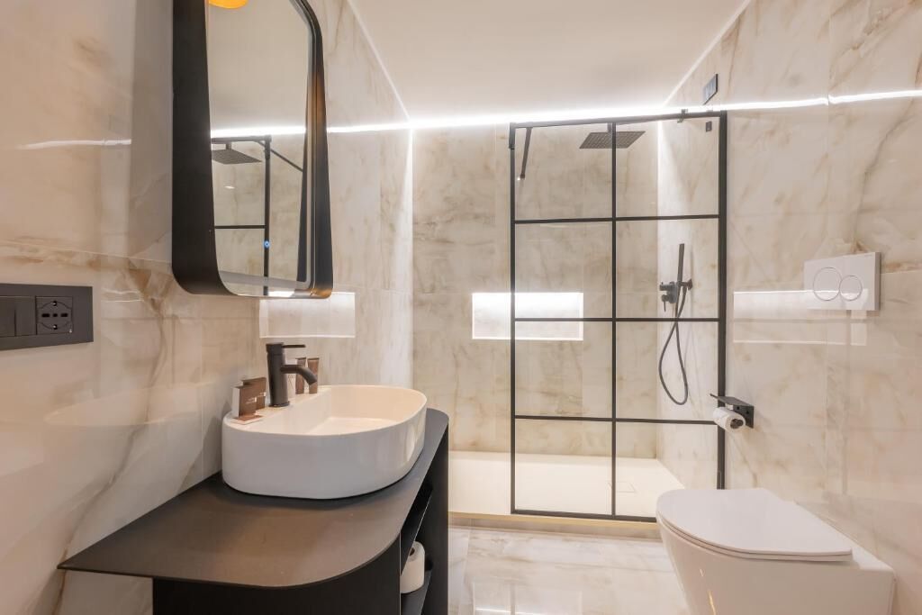 A modern bathroom with a round sink, a toilet, and a glass-enclosed shower.