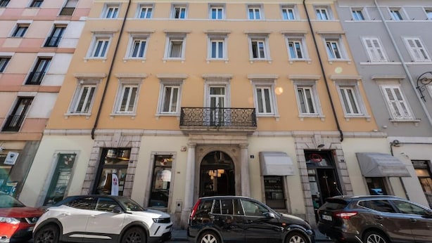 A multi-story building with a central entrance, several windows, and a small balcony.