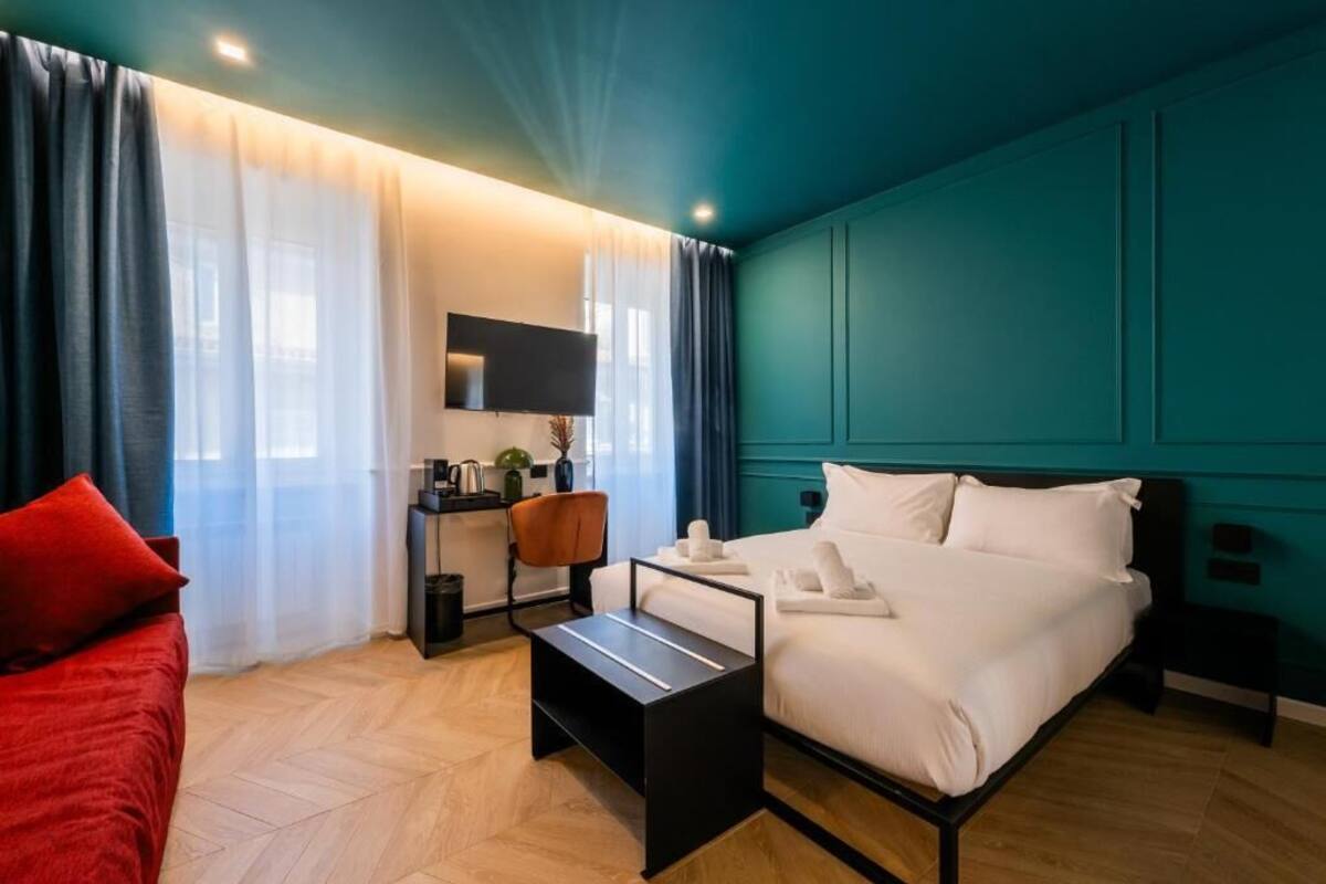 A modern hotel room with a bed, a desk, and a TV.