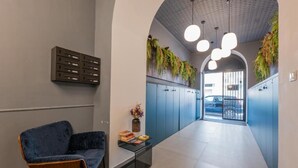 A modern hallway with a blue wall, a blue chair, a small table with books, and a plant.