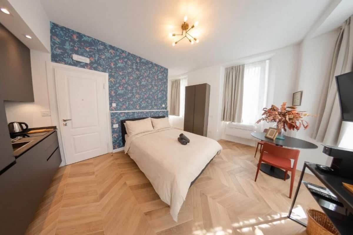 Egy modern hálószoba, amelyben található egy ágy, egy íróasztal, egy szék és egy televízió.
