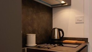 Une cuisine moderne dotée d’un évier en acier inoxydable, d’une bouilloire et d’un récipient blanc.