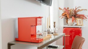 Une cuisine moderne avec une machine à café rouge, une table en verre et une chaise rouge.