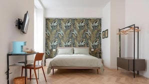Une chambre à coucher avec un lit, un bureau et une chaise, une télévision et une armoire.