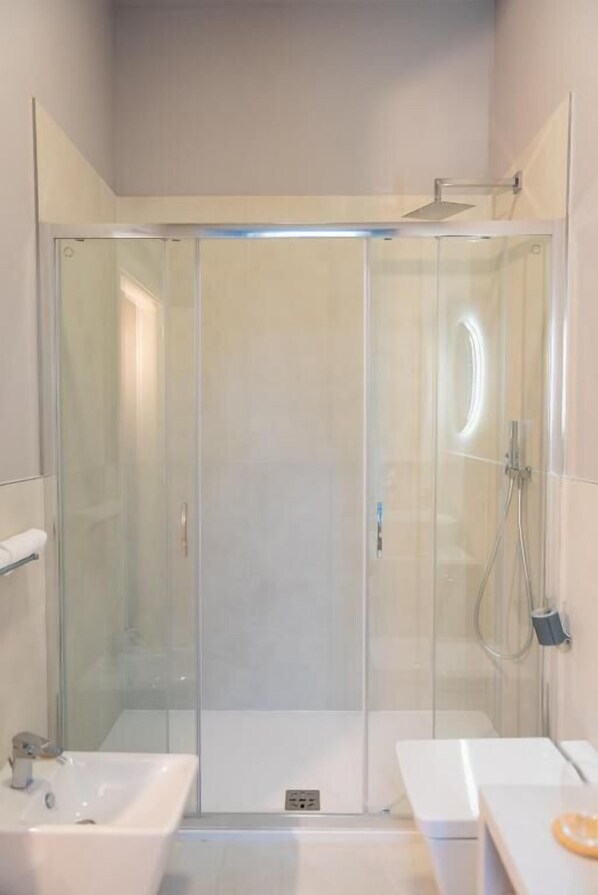 A modern bathroom with a glass-enclosed shower, a sink, and a towel rack. - Sophia Boutique Suites (Trieste)