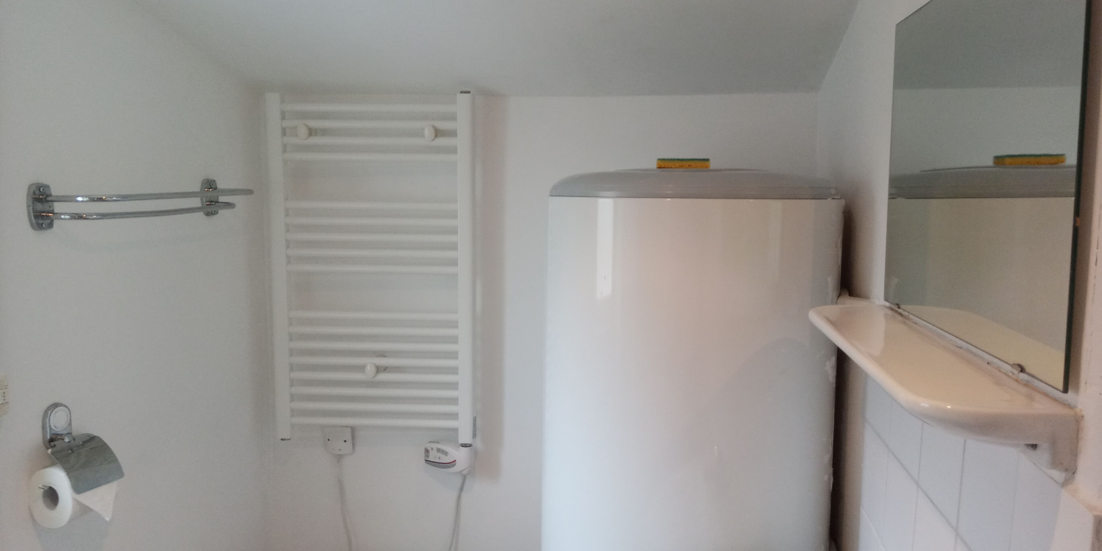 Een badkamer met toilet, handdoekhouder en spiegel.