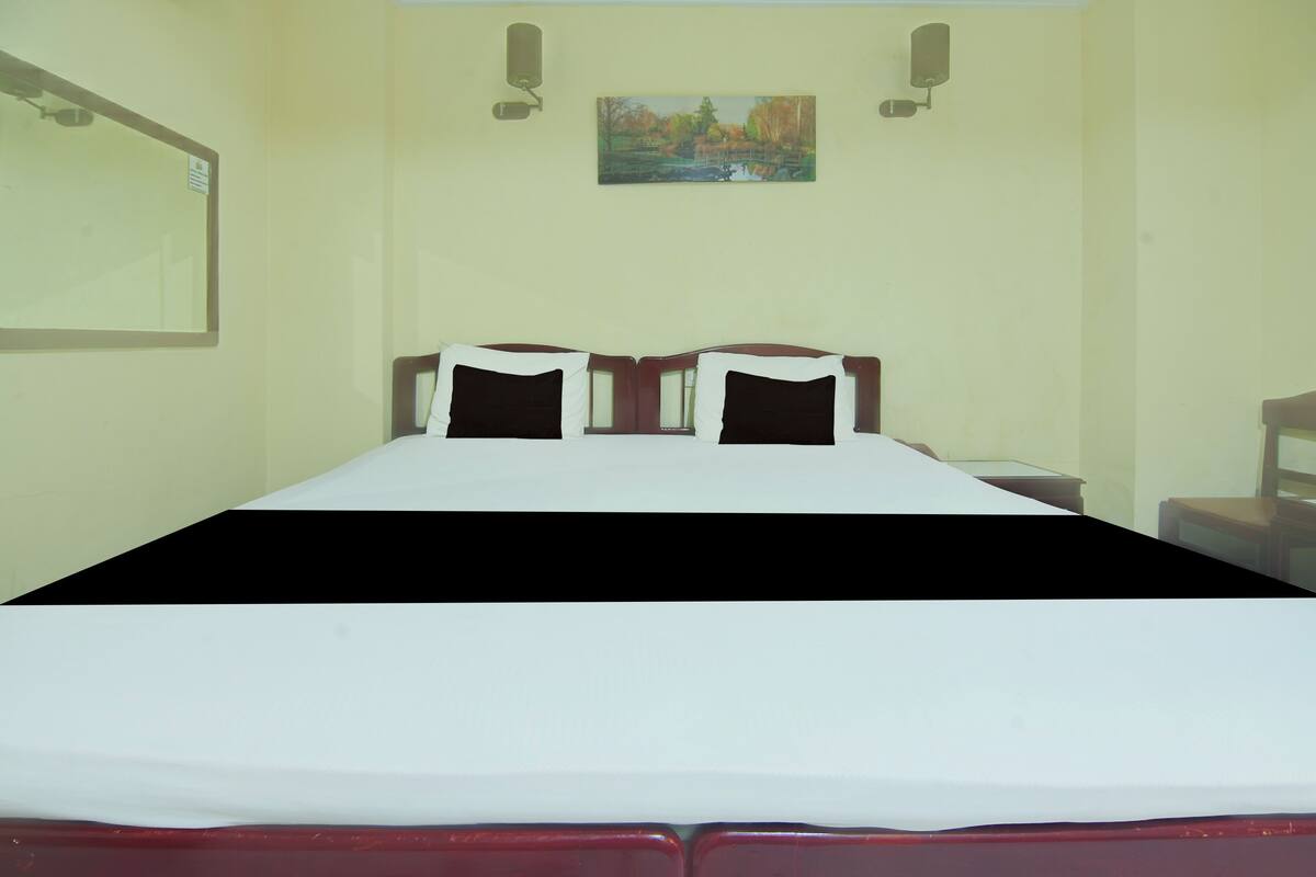 Ein Hotelzimmer mit einem Bett, zwei Nachttischen, einem Wandbild und einem Spiegel.