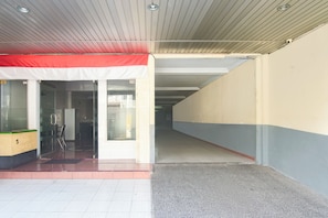A building entrance with a red and white awning, a glass door, and a tiled floor.