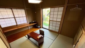 Ein traditioneller japanischer Raum mit Tatami-Böden, einem niedrigen Holztisch, einem Stuhl und verschiebbaren Shoji-Türen.