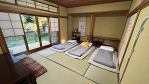 Ein traditioneller japanischer Raum mit Tatami-Boden, Schiebetüren und einem Bett mit Futon.