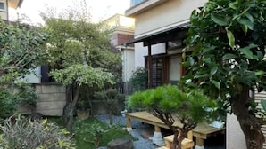 Ein traditioneller japanischer Garten mit Kiesweg, hölzernem Bank und verschiedenen Pflanzen.