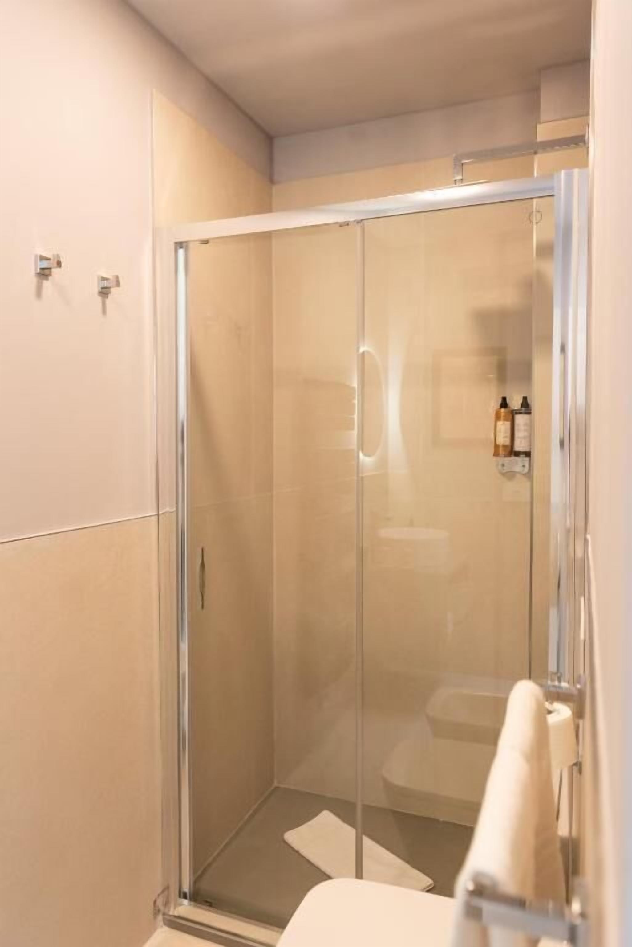 A glass-enclosed shower stall with a white towel hanging on the door.