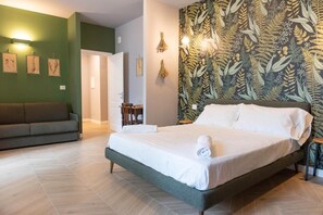 Un dormitorio con cama, sofá y pared con estampado de hojas.