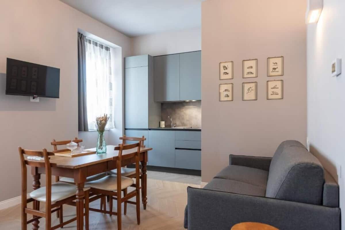 A compact living space with a dining area, kitchenette, and a gray sofa.