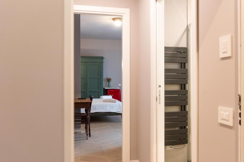 Un pasillo que conduce a un dormitorio con una cama, una mesita de noche y un aparador.