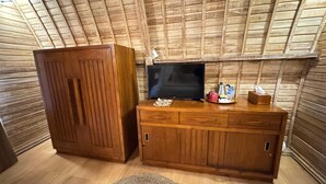 Ein Zimmer mit Holzbalkendecke, einem Fernseher auf einer Holzkommode und einem kleinen Teppichboden.