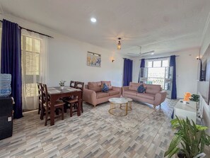 Una sala de estar con una mesa de comedor, dos sofás, una mesa de centro y un ventilador de techo.