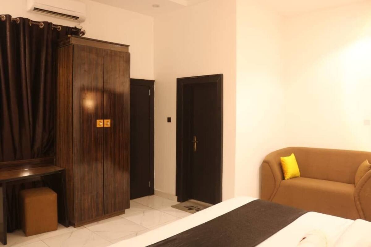 Ein Hotelzimmer mit Bett, Schrank, Schreibtisch und einer Sitzecke.