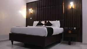 A modern bedroom with a dark wood headboard, a white bedspread, and two bedside tables with lamps. - VICTORIAN BLOOM HOTEL AND RESORT (Asaba)