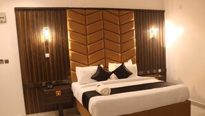 A neatly made bed with white and black bedding, a wooden headboard with a chevron pattern, and a small bedside table with a lamp. - VICTORIAN BLOOM HOTEL AND RESORT (Asaba)