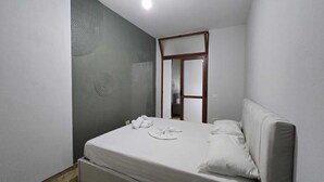 A bedroom with a bed, a mirror, and a door leading to a bathroom. - Tirent Apartment-One Bedroom Central (Tirana)