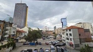 A parking lot with multiple cars, surrounded by buildings of varying heights and architectural styles. - Tirent Apartment-One Bedroom Central (Tirana)