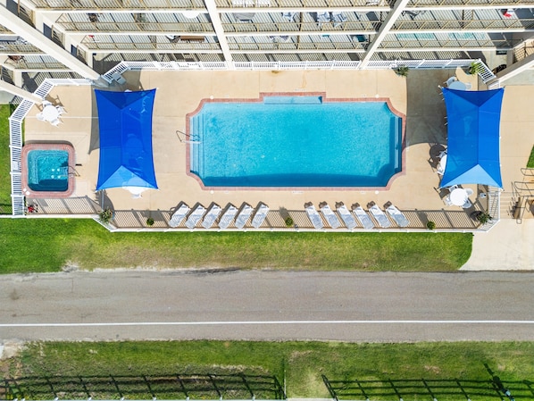 An aerial view of a hotel with a large rectangular swimming pool surrounded by sun loungers and a smaller hot tub. - Tradewinds - Laguna Reef Waterfront Condo unit 305 (Rockport)