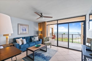 A living room with a sofa, coffee table, and a view of the ocean through large glass doors.