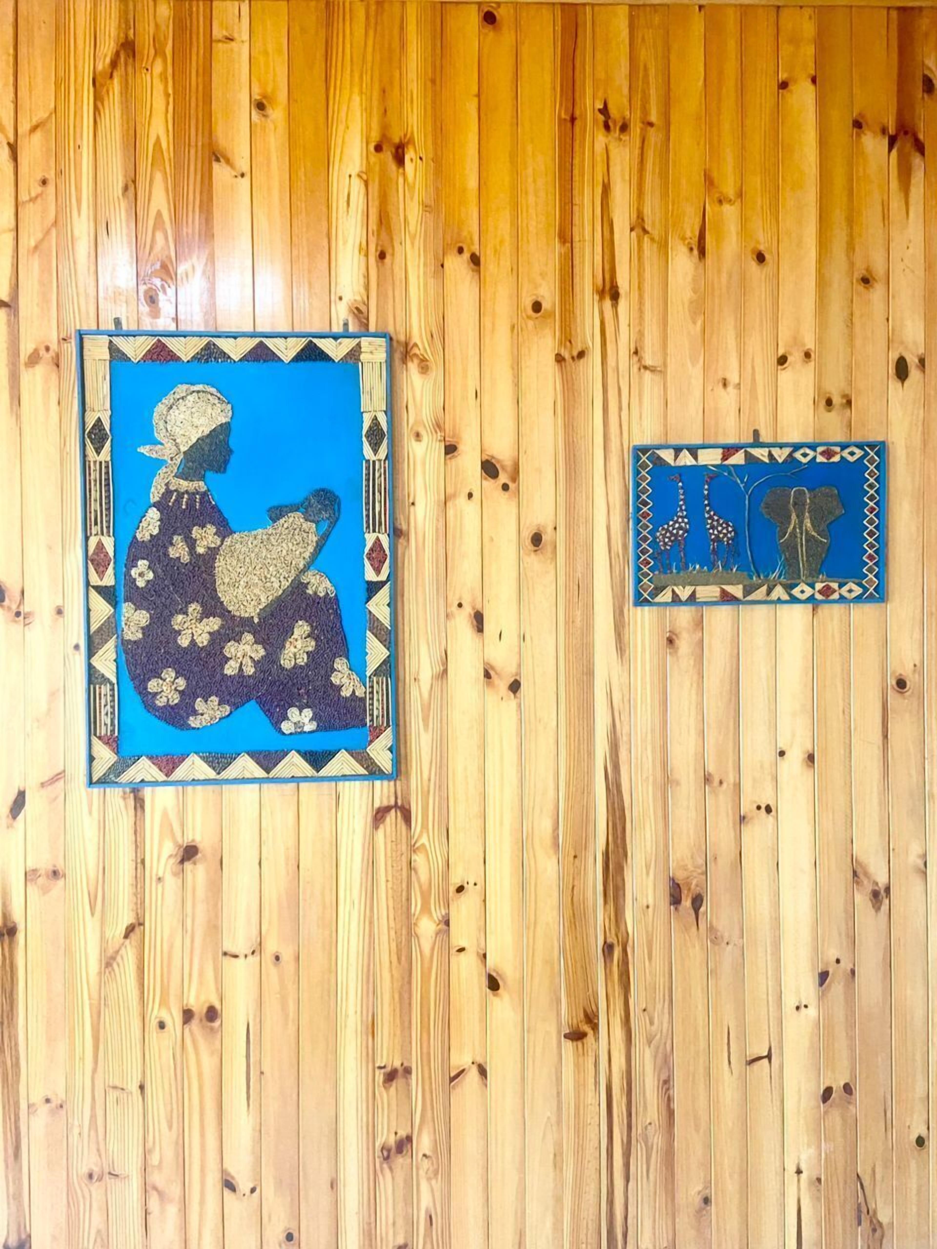 Deux œuvres d’art encadrées sont accrochées à un mur en bois.