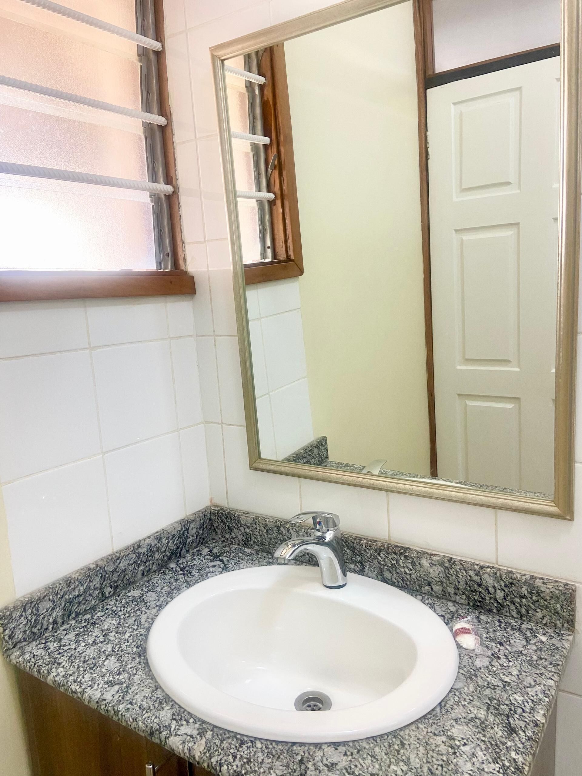 A bathroom with a granite countertop sink, a mirror, and a door.