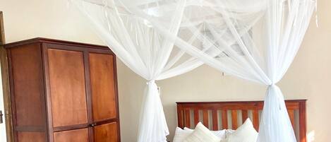 Una cama con dosel, cabecera de madera y ropa de cama blanca.