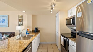 A compact kitchen with a granite countertop, stainless steel appliances, and a coffee maker. - Paradise | Waterfront Comfort at Laguna Reef 411 (Rockport)