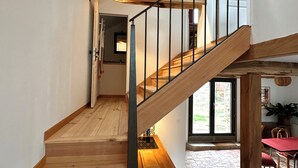 Eine Holztreppe mit Metallgeländer, die zu einer oberen Etage führt. Ein Oberlicht über der Treppe lässt natürliches Licht herein.
