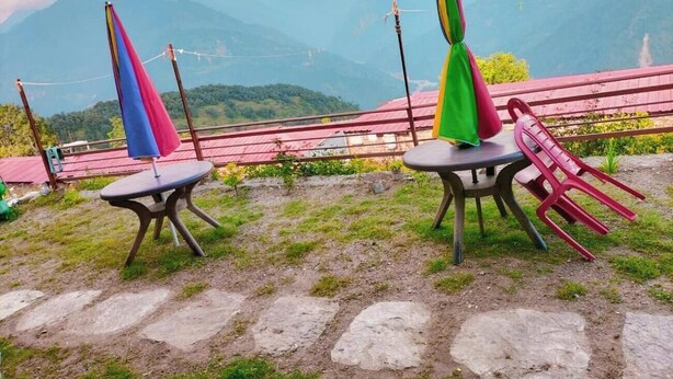 Una terraza con dos mesas y sillas, con vistas a un paisaje montañoso.